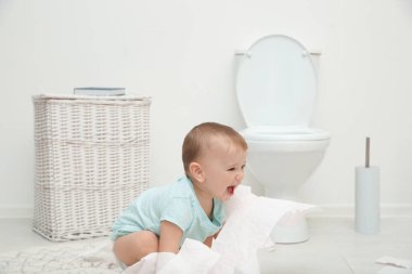 Banyoda tuvalet kağıdı ile oynarken şirin yürümeye başlayan çocuk