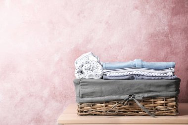 Bebek giyim renk duvarının yakınında masada sepetle. Metin için yer