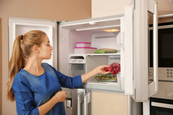 Ung Kvinna Med Frysta Körsbär Nära Öppna Kylskåpet Hemma — Stockfoto