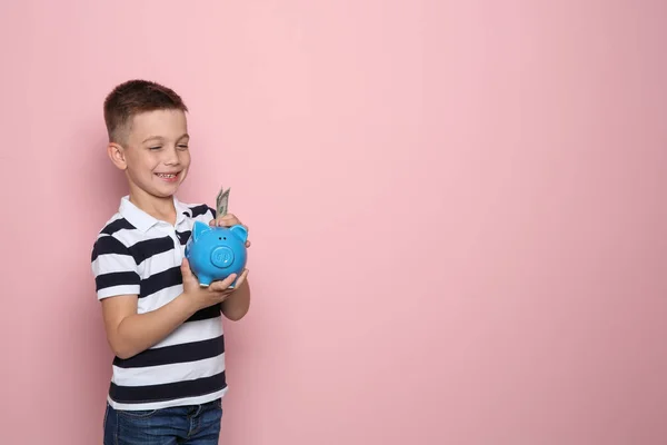 Kleiner Junge Legt Geld Sparschwein Auf Farbigem Hintergrund Raum Für — Stockfoto