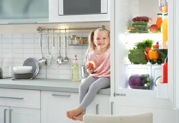 Χαριτωμένο Μικρό Κορίτσι Μήλο Που Κάθονται Κοντά Στο Ανοιχτό Ψυγείο — Φωτογραφία Αρχείου