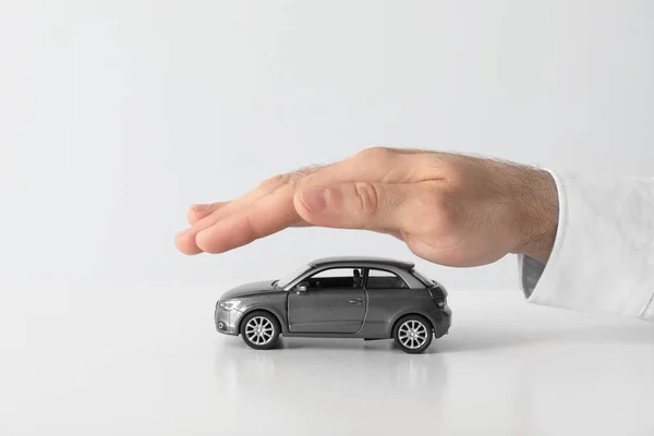 Männlicher Versicherungsvertreter Deckt Spielzeugauto Auf Weißem Hintergrund Nahaufnahme — Stockfoto