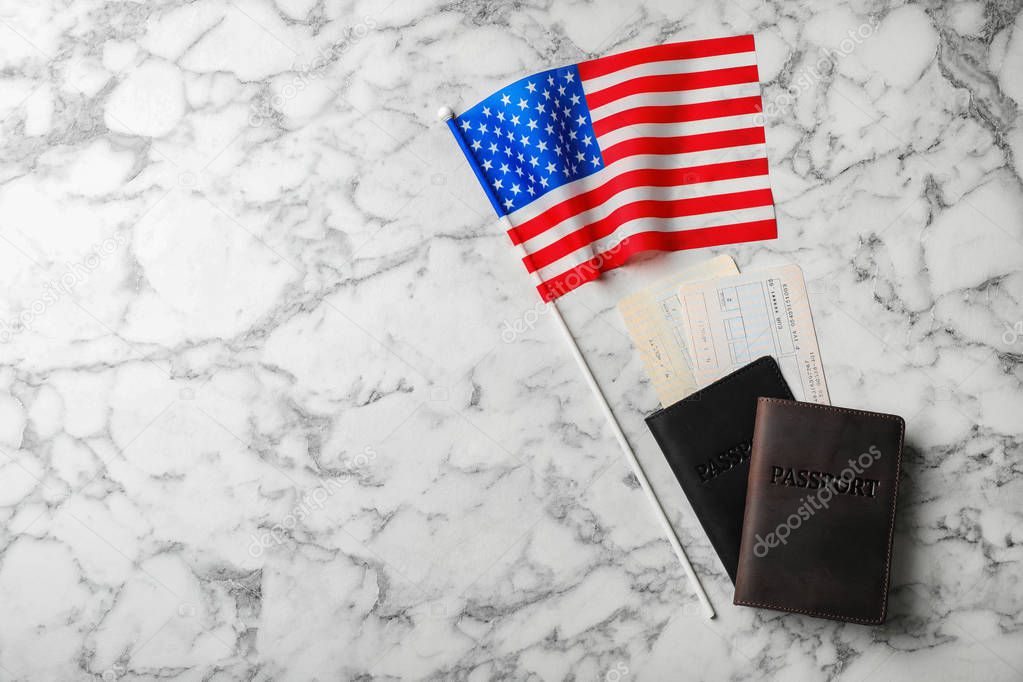 Flat lay composition with flag of USA and passports on marble background. Space for text