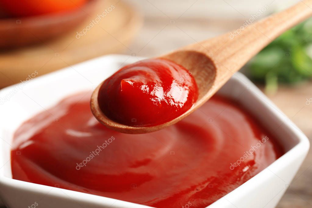 Spoon and bowl with homemade tomato sauce on table, closeup