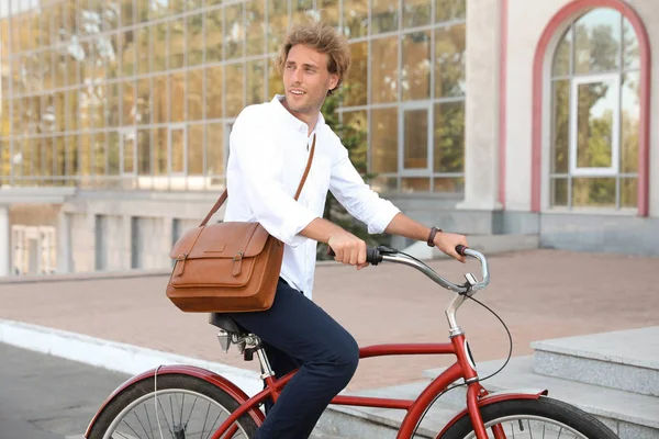 Attractive man riding bike on city street