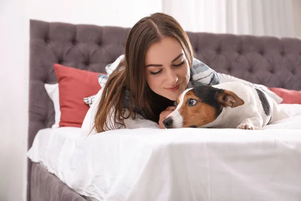 自宅のベッドで横になっている彼女の犬と美しい女性 — ストック写真