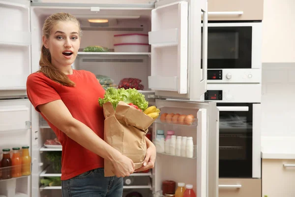 Junge Frau Mit Frischen Lebensmitteln Papiertüte Der Nähe Von Kühlschrank — Stockfoto