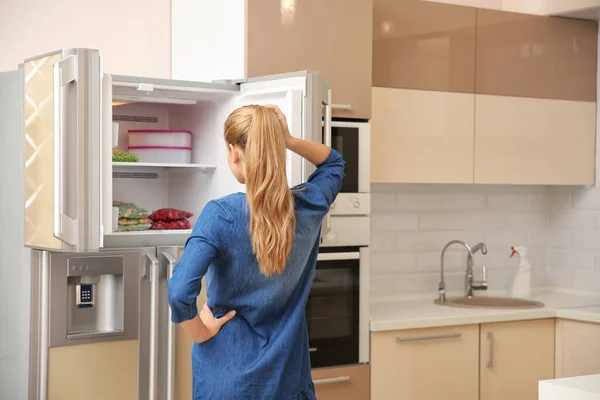 Νεαρή Γυναίκα Στέκεται Κοντά Στο Ανοιχτό Ψυγείο Στην Κουζίνα — Φωτογραφία Αρχείου