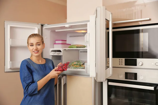 Junge Frau Mit Tiefgefrorenen Kirschen Der Nähe Des Offenen Kühlschranks — Stockfoto