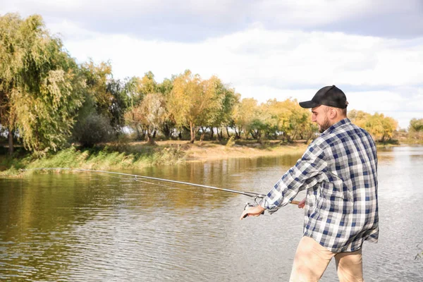 Man with rod fishing at riverside. Recreational activity