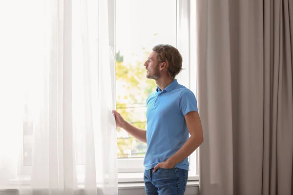 Jeune Homme Debout Près Fenêtre Avec Des Rideaux Ouverts Maison — Photo