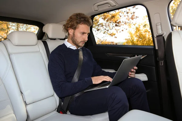 Arabanın Arka Koltuğunda Dizüstü Bilgisayar Kullanan Genç Yakışıklı Adam — Stok fotoğraf