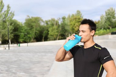 Genç adam sokakta protein içeceği içme