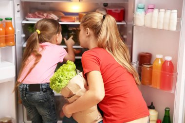 Genç Anne ve kızı ile kağıt torba gıda evde buzdolabı yakınındaki dolu