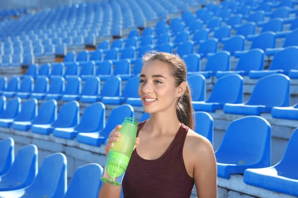 晴れた日にスタジアムで水のボトルを保持しているスポーティな女性 — ストック写真