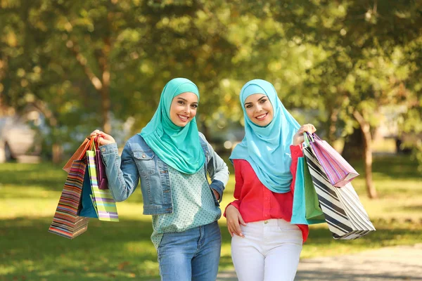 Muslim women with shopping bags walking in park