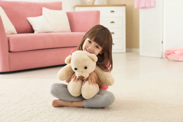 Cute little girl playing with teddy bear at home