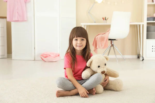 Cute little girl playing with teddy bear at home