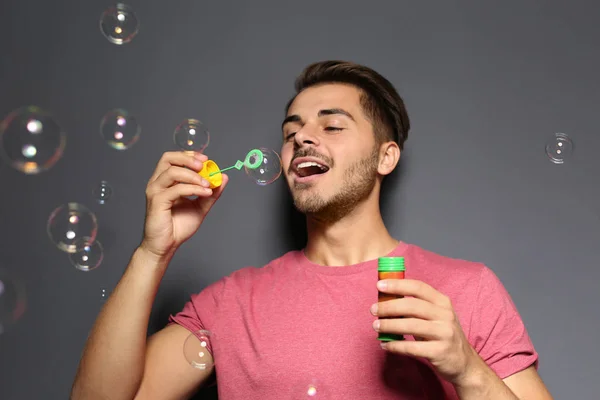 Joven Hombre Soplando Burbujas Jabón Fondo Color — Foto de Stock