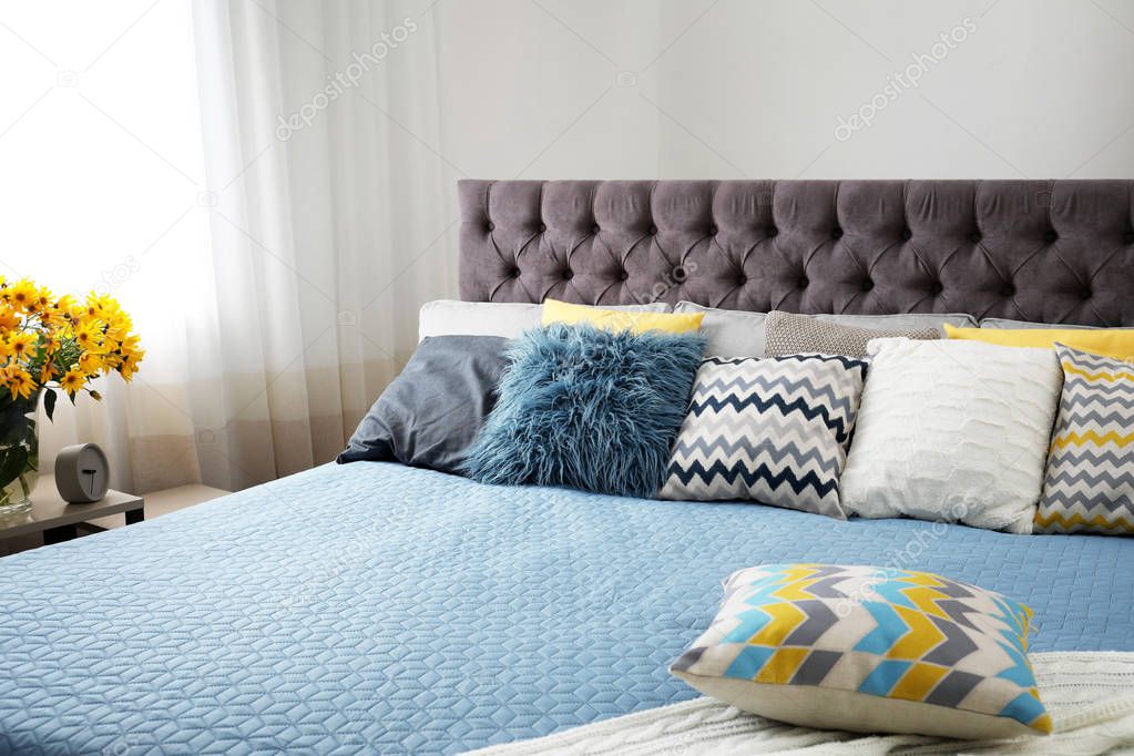 Different pillows on bed in room. Idea for interior decor