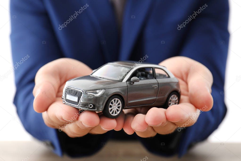 Insurance agent holding toy car over table, focus on hands