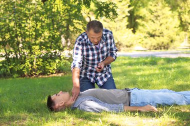 Yoldan geçen bilinçsiz adam açık havada darbe denetlerken ambulans çağırma. İlk yardım