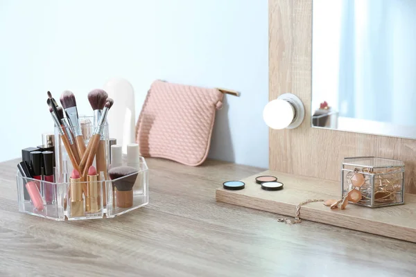Organizer with cosmetic products for makeup on table near mirror