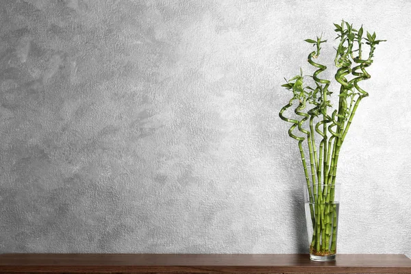 桌上有竹植物在玻璃花瓶附近的色墙 文本的空间 — 图库照片