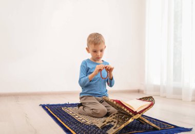 Tesbih ve Kur'an halıya kapalı dua küçük Müslüman çocuk