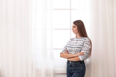 Genç kadının açık perdeleri evde penceresiyle yanına. Metin için yer