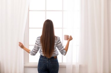Pencere perdeleri evde açmayı kahve olan kadın