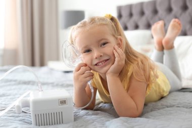 Little girl with asthma machine in bedroom. Space for text clipart