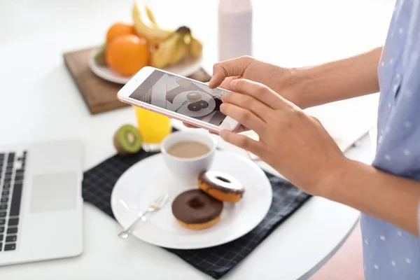 Food blogger taking photo of breakfast at home, focus on phone display