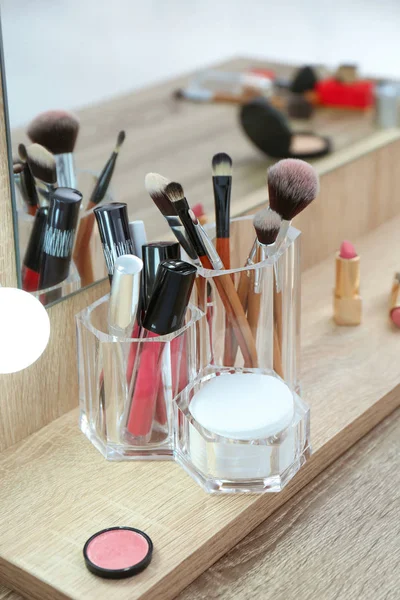 Organizer with cosmetic products for makeup on table near mirror