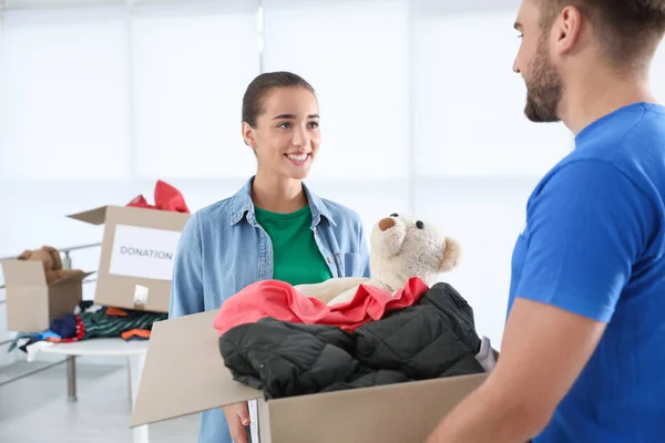 Mujer Joven Dando Caja Con Donaciones Voluntarios Varones Interior — Foto de Stock