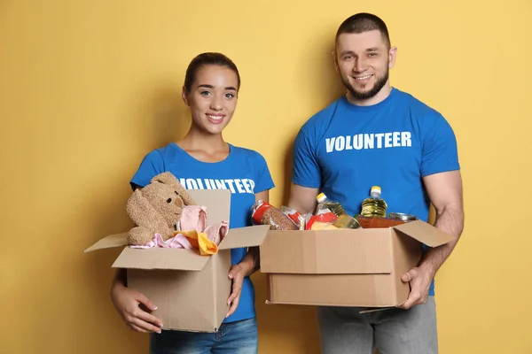 Jóvenes Voluntarios Sosteniendo Cajas Con Donaciones Sobre Fondo Color — Foto de Stock
