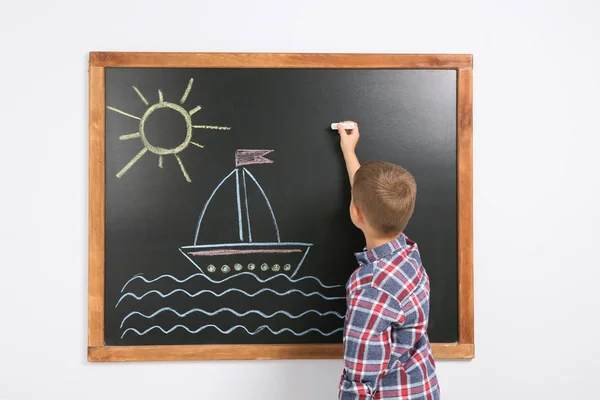 小さな子供が黒板にカラフルなチョークで船を描画 — ストック写真