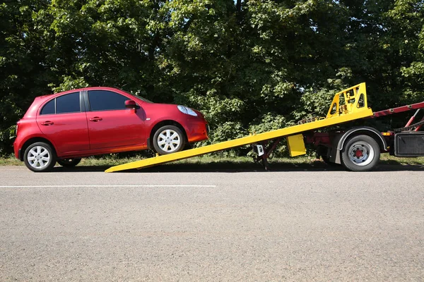 Broken car and tow truck on country road