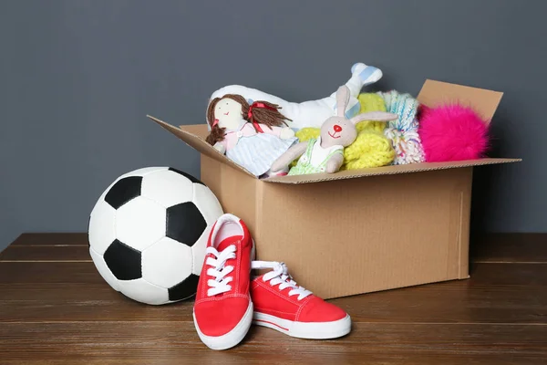 Caixa Doação Sapatos Brinquedos Roupas Mesa Perto Parede Cinza — Fotografia de Stock