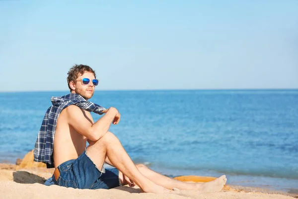 ビーチに座っている若い男 テキストのためのスペース — ストック写真