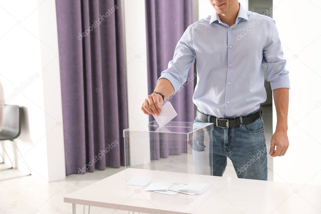 Man putting ballot paper into box at polling station