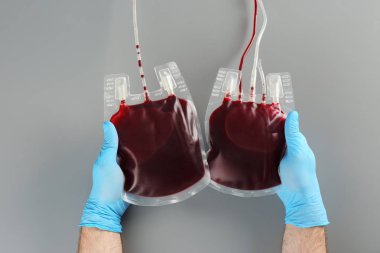 Doktor kan paketleri gri arka plan üzerinde üstten görünüm elinde eldiven. Bağış gün