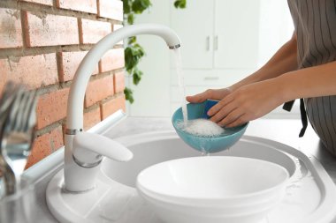 Mutfak lavabosunda bulaşık yıkayan bir kadın, yakın çekim manzarası. Temizlik işleri