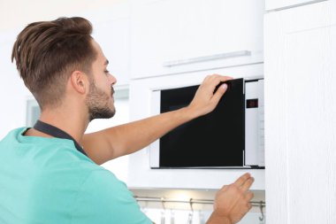 Genç adam evde modern mikrodalga fırın kullanma