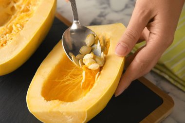 Kadın spagetti squash masada, closeup tohum kaldırılıyor