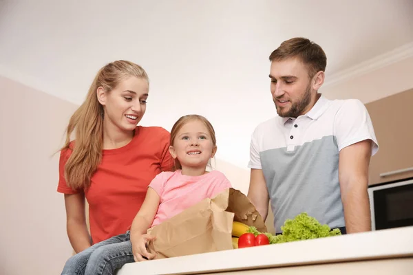 幸せな若い家族は自宅の紙袋に健康食品と — ストック写真
