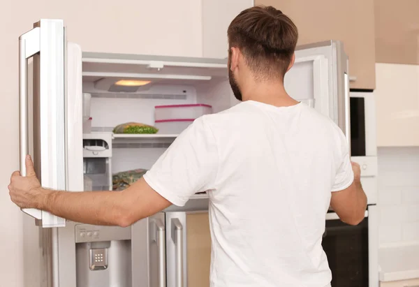 Молодой Человек Ищет Еду Холодильнике Дома — стоковое фото