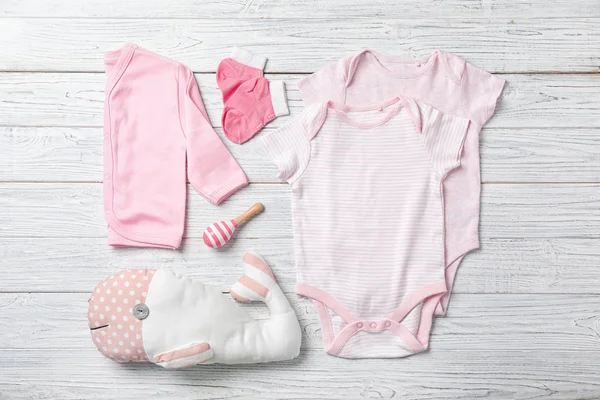 Ahşap arka plan üzerinde şık bebek giysileri ile düz yatıyordu kompozisyon