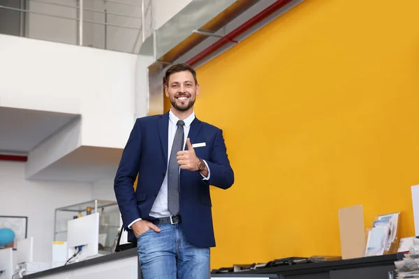 Salesman standing in modern auto dealership. Buying new car