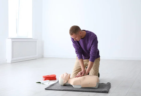 Man practicing first aid on mannequin indoors